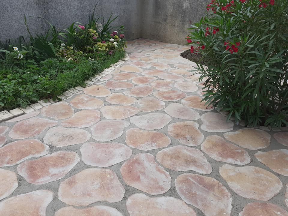 Allée de jardin en pierre reconstituée posée en opus incertum, bordée d'une rive maçonnée.