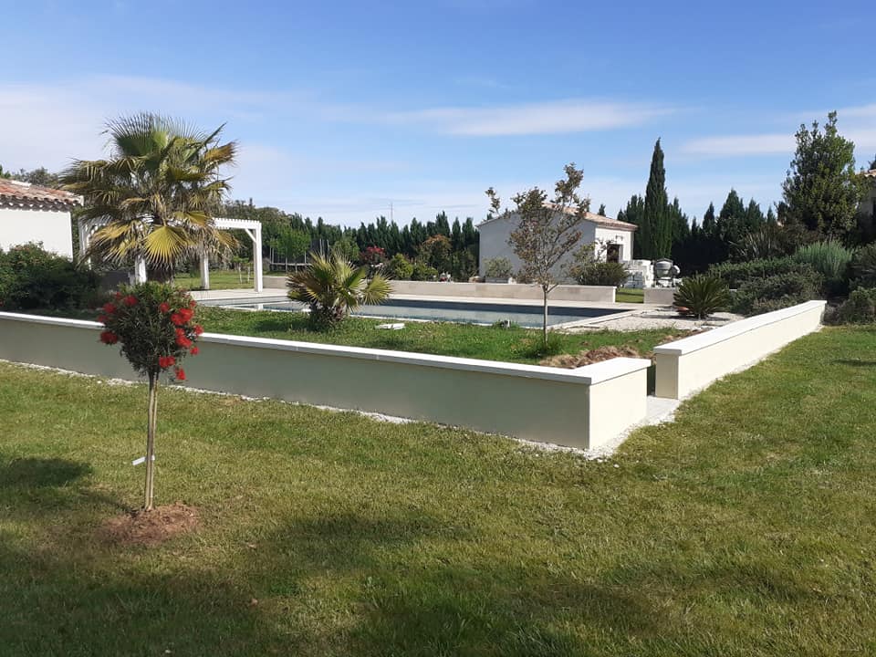 Mur de soutènement enduit délimitant les abords d'une piscine.